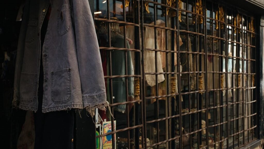 Veste de travail vintage suspendue devant la vitrine grillagée d'une friperie
