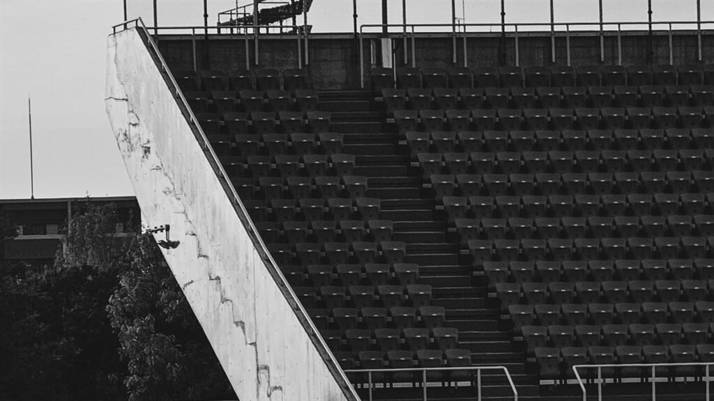 Tribune de stade vide en noir et blanc, gradins de béton et sièges alignés